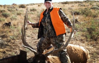 man posing with an elk and horns