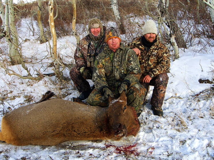 group posing with an elk and horns in winter
