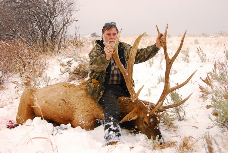 man posing with an elk and horns in winter