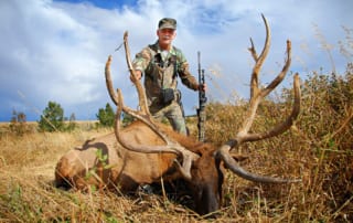 man posing with an elk and horns