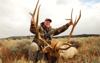 man posing with an elk and horns