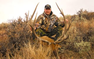 man posing with an elk and horns