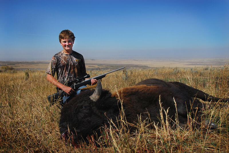 young man posing with a buffalo