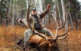 man posing with an elk and horns