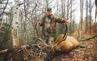 man posing with an elk and horns