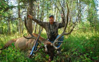 man posing with an elk and horns