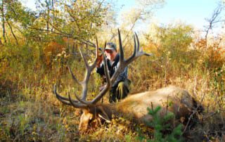 man posing with an elk and horns