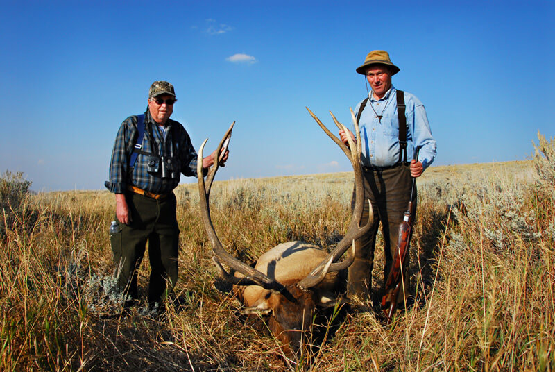 men posing with an elk and horns