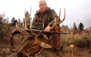 man posing with an elk and horns