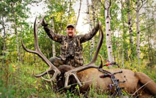 man posing with an elk and horns