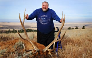 man posing with an elk and horns