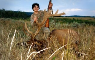 man posing with an elk and horns