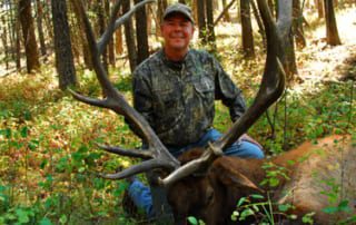 man posing with an elk and horns