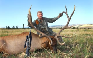 man posing with an elk and horns