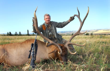 man posing with an elk and horns