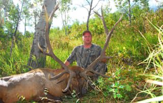 man posing with an elk and horns