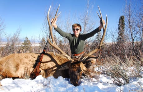 young man posing with an elk and horns