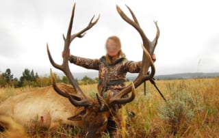 person posing with an elk and horns