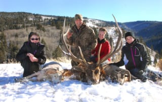 group posing with an elk and horns in winter