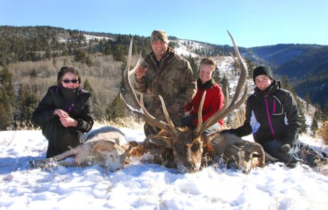 group posing with an elk and horns in winter