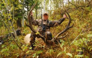 man posing with an elk and horns