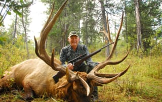 man posing with an elk and horns