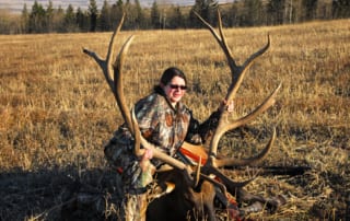 woman posing with an elk and horns