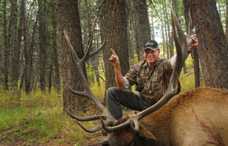 man posing with an elk and horns