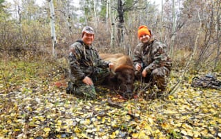 two men posing with a buffalo