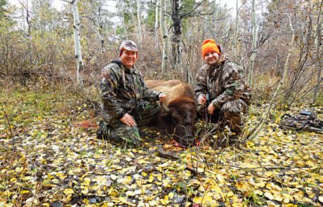 two men posing with a buffalo