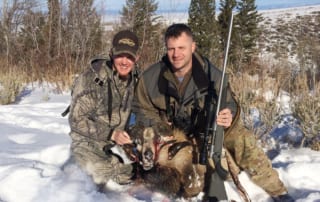 two men posing with a ram