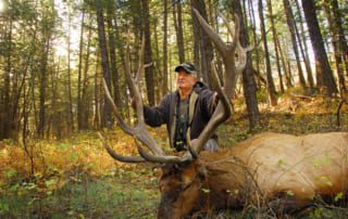 man posing with an elk and horns