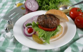 An elk burger made from a recipe of ground elk, tomato, onion, lettuce, and buns