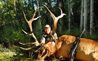 A hunter posing with an elk after a successful elk hunt