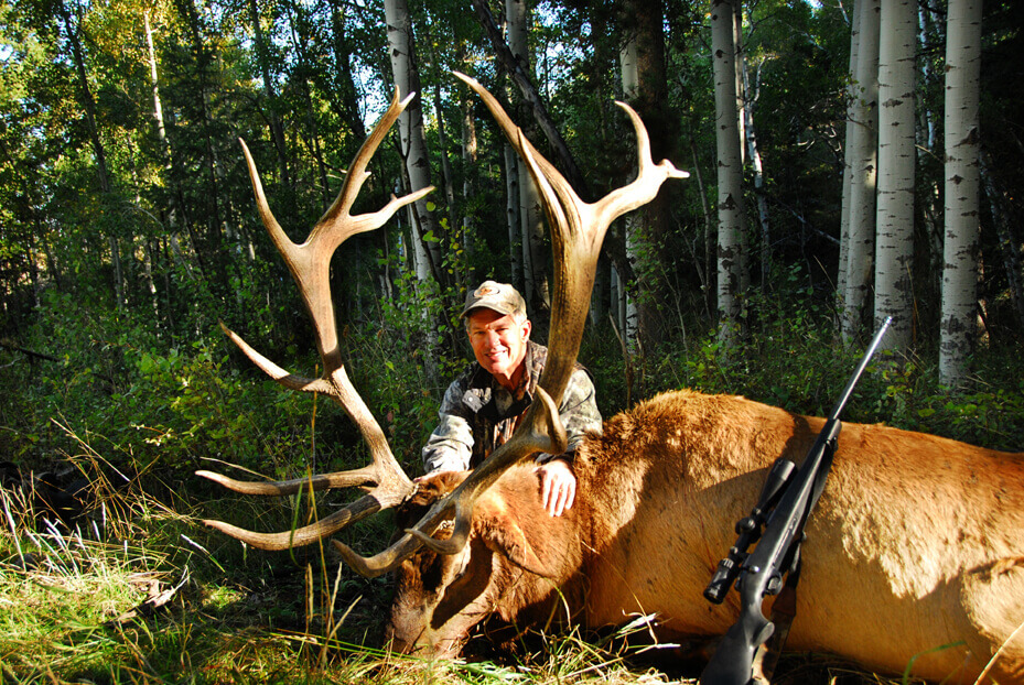 A hunter posing with an elk after a successful elk hunt