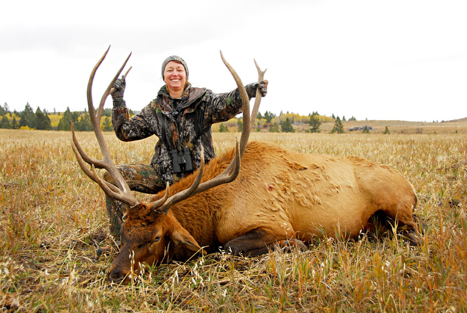 Idaho Elk Hunt: A woman smiles while holding the antlers of her trophy elk.