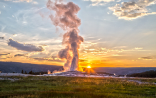 Things to Do in Yellowstone National Park: A stunning display of geothermal power as Old Faithful erupts in the distance.