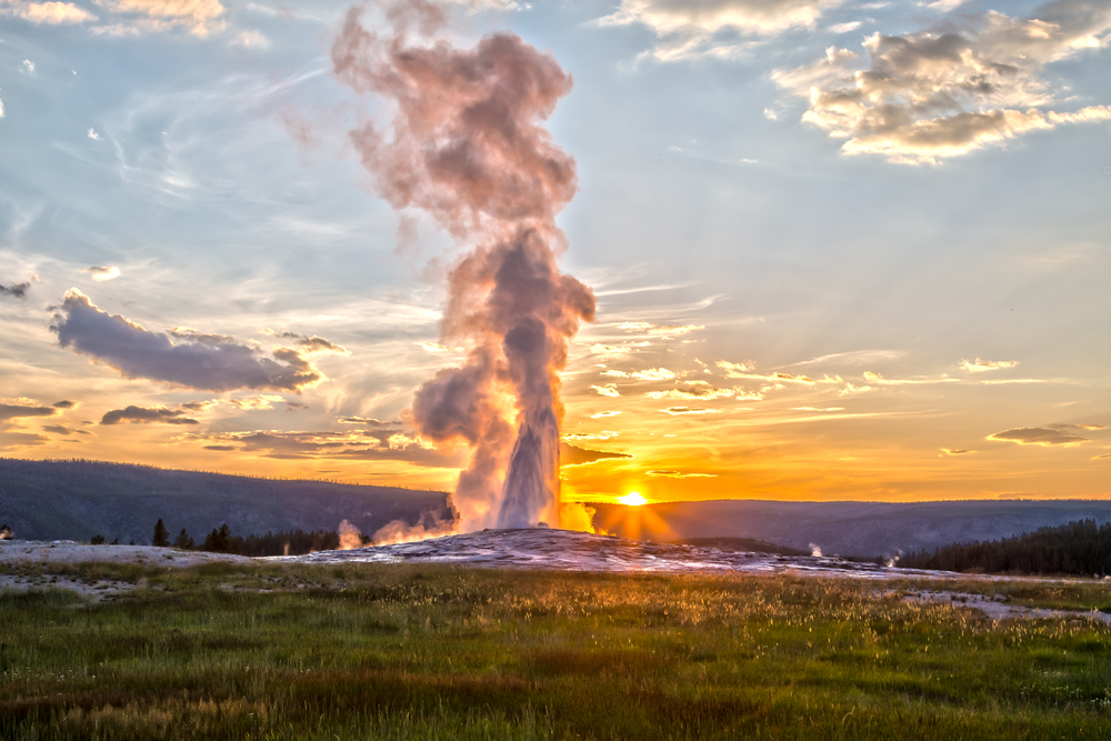Things to Do in Yellowstone National Park: A stunning display of geothermal power as Old Faithful erupts in the distance.