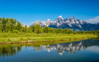 Jackson Hole Experiences: A stunning landscape image of the Teton Range rising sharply with Jenny Lake in the foreground.