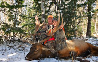 A father and son pose with a massive elk during a winter hunting trip