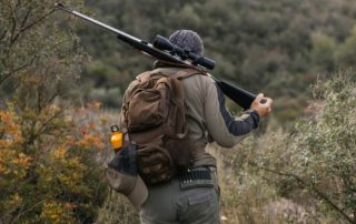 A hunter walking with his rifle over his shoulder on unfamiliar hunting land