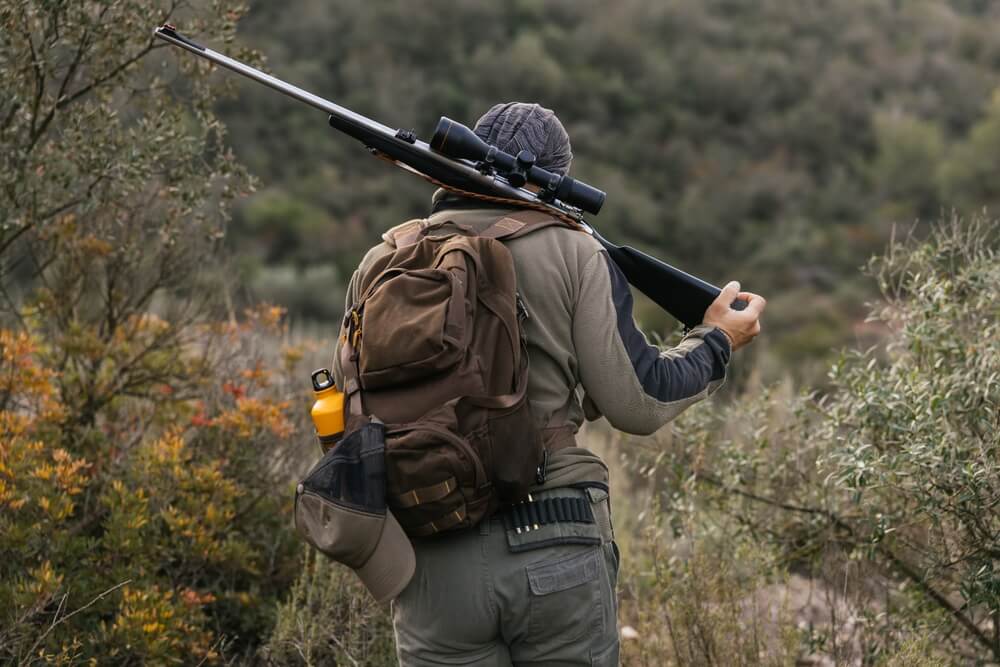 A hunter walking with his rifle over his shoulder on unfamiliar hunting land
